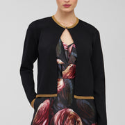 Woman wearing a black cardigan over a floral dress on a light gray background