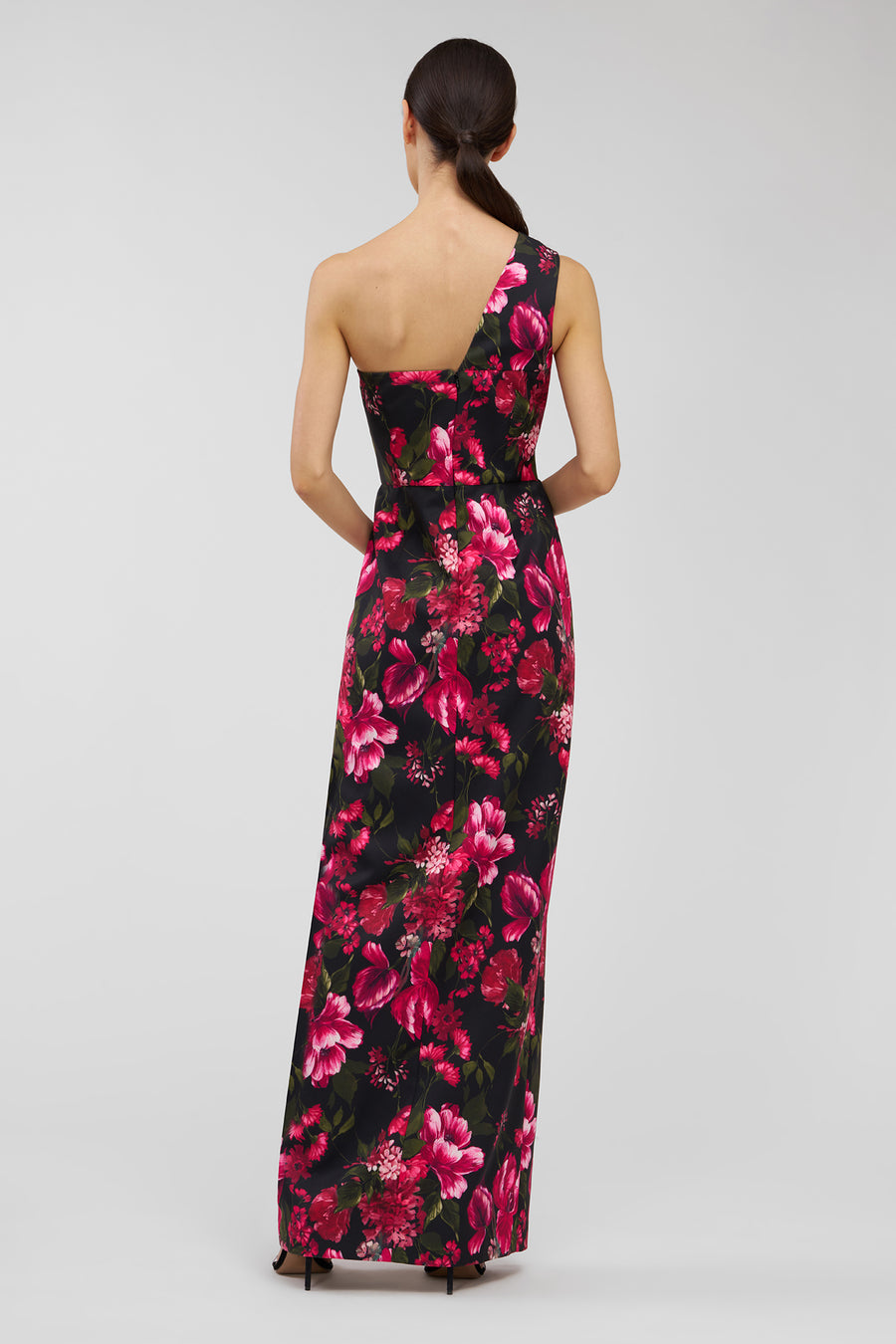 Woman wearing a floral one-shoulder dress on a light gray background