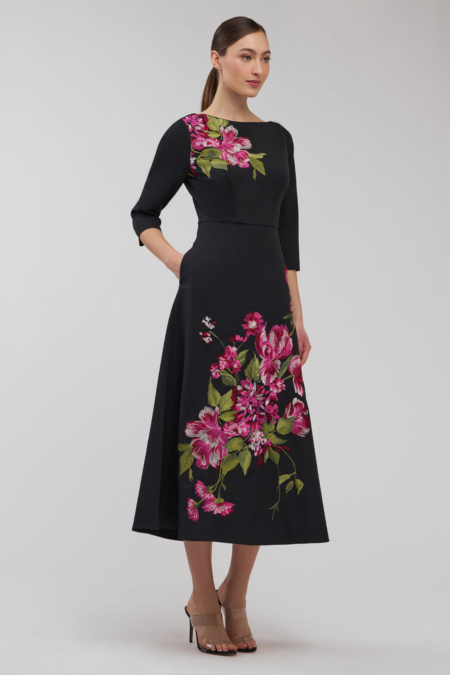 Woman wearing a black dress with floral patterns on a white background