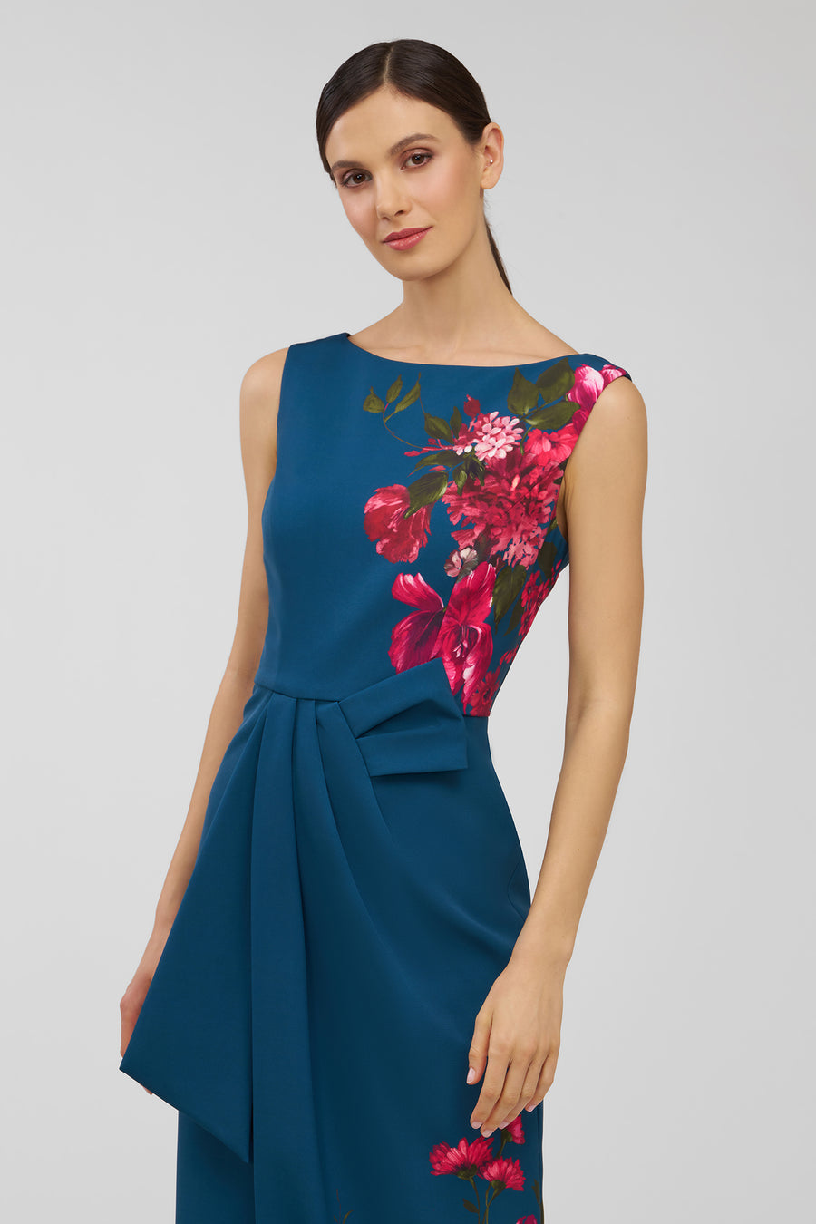 Woman wearing a blue dress with pink floral patterns on a gray background