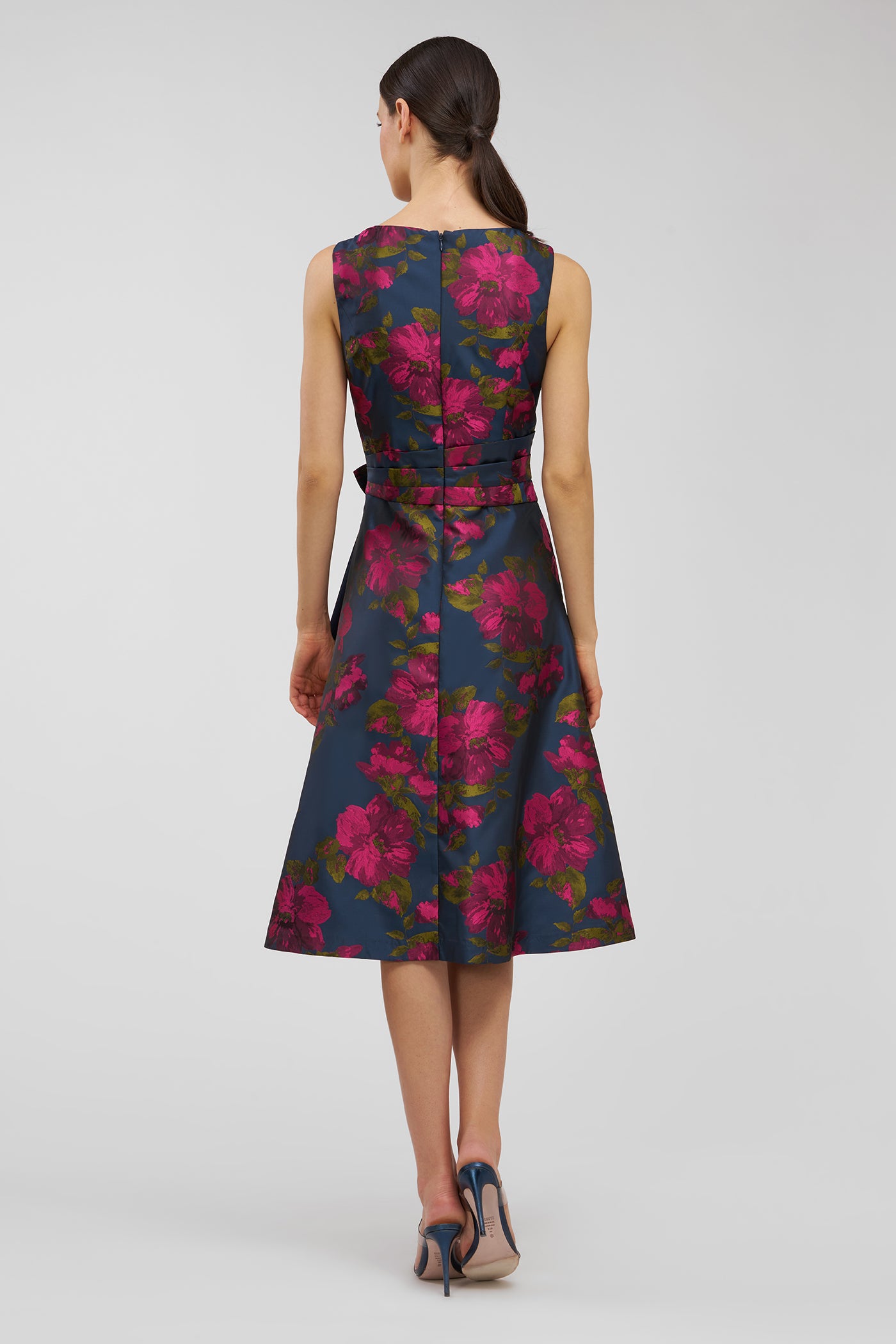 Woman wearing a sleeveless floral dress with a belt on a white background