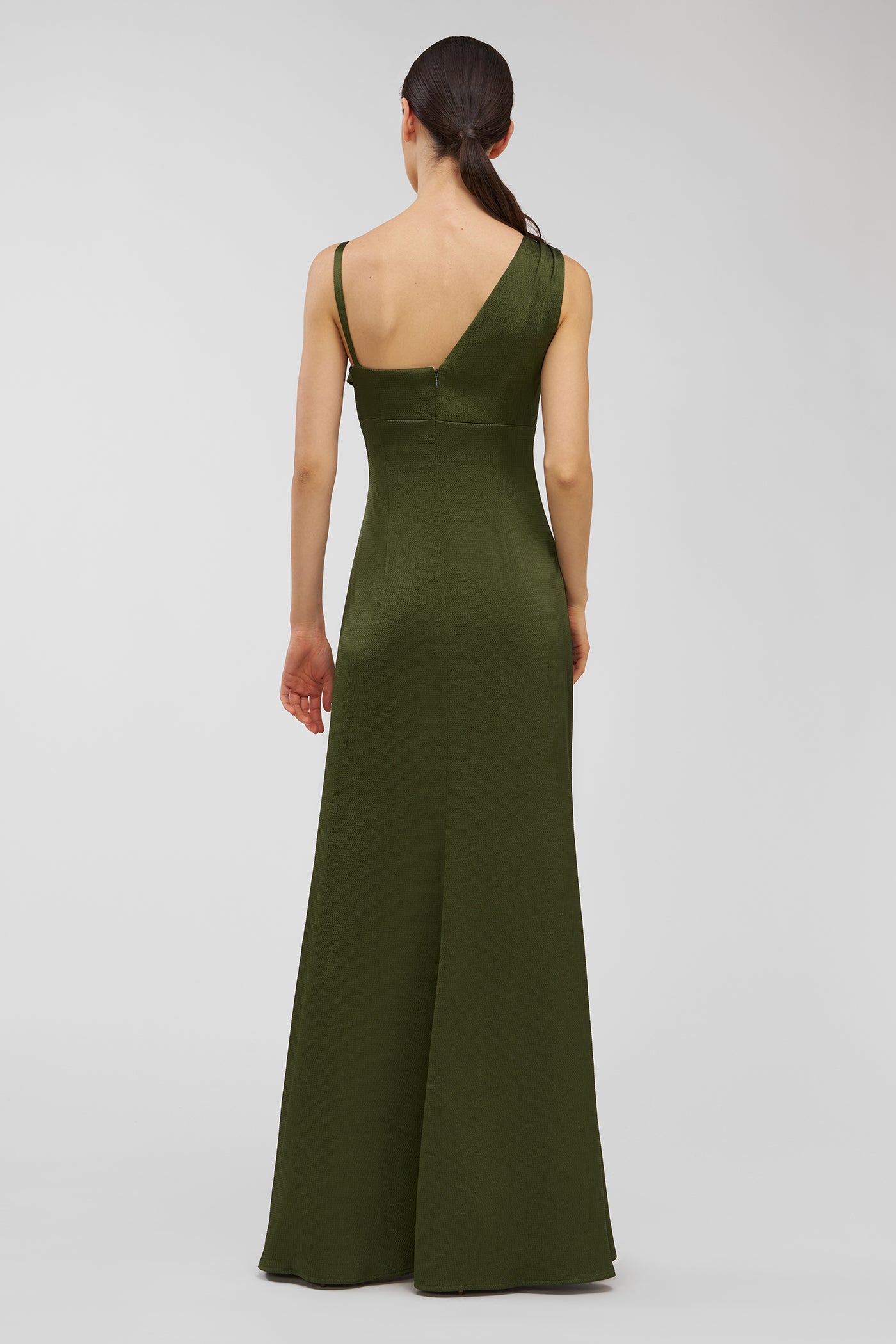 Woman wearing a green one-shoulder dress on a white background