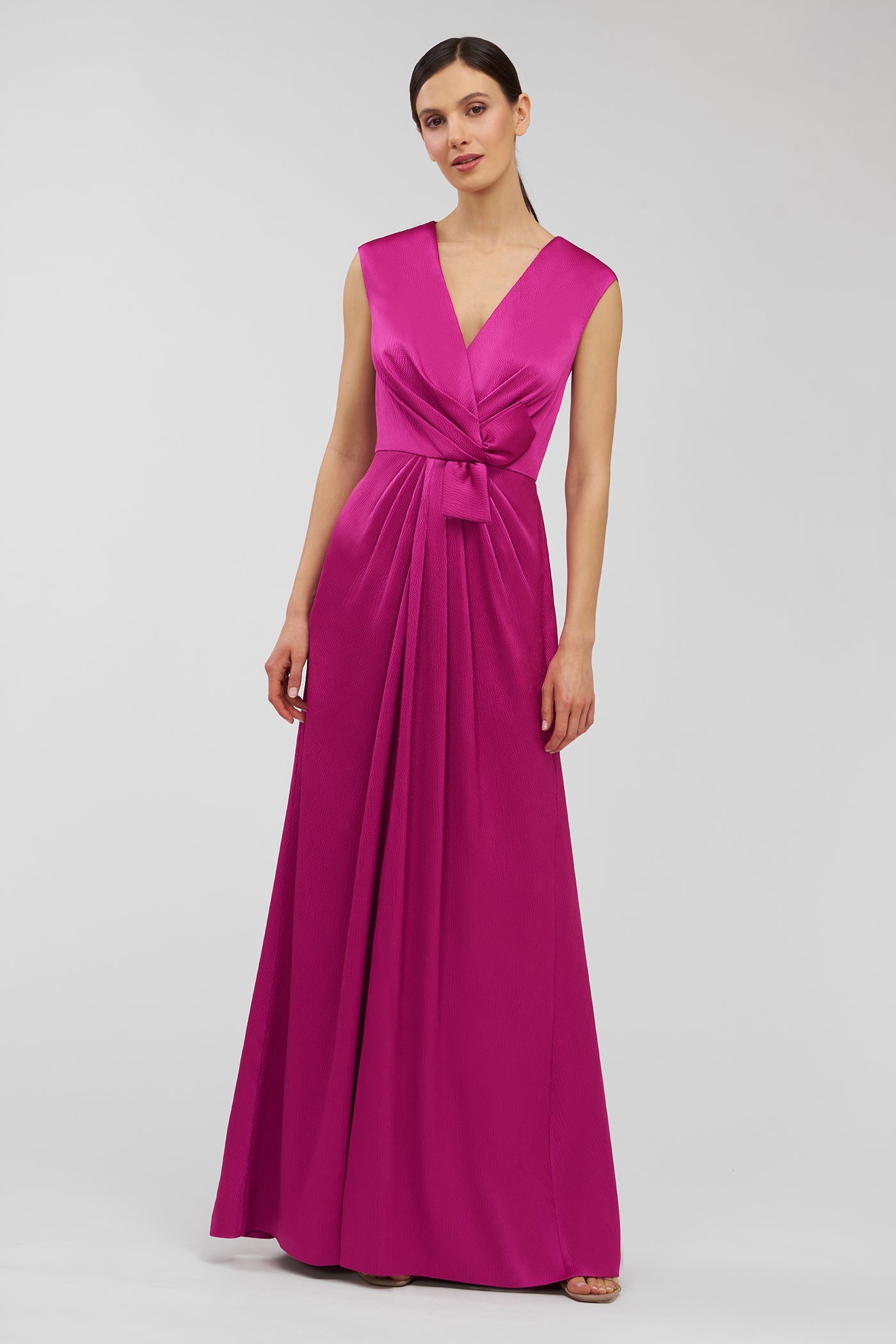 Woman wearing a vibrant pink gown on a light gray background