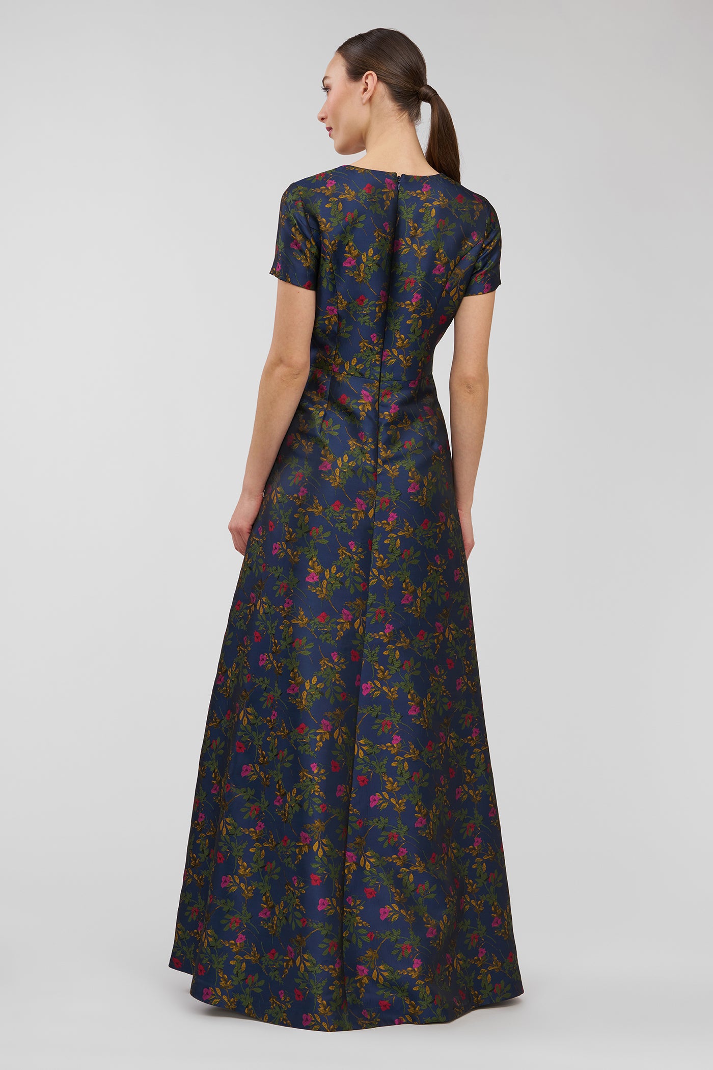 Woman wearing a long floral dress on a plain background