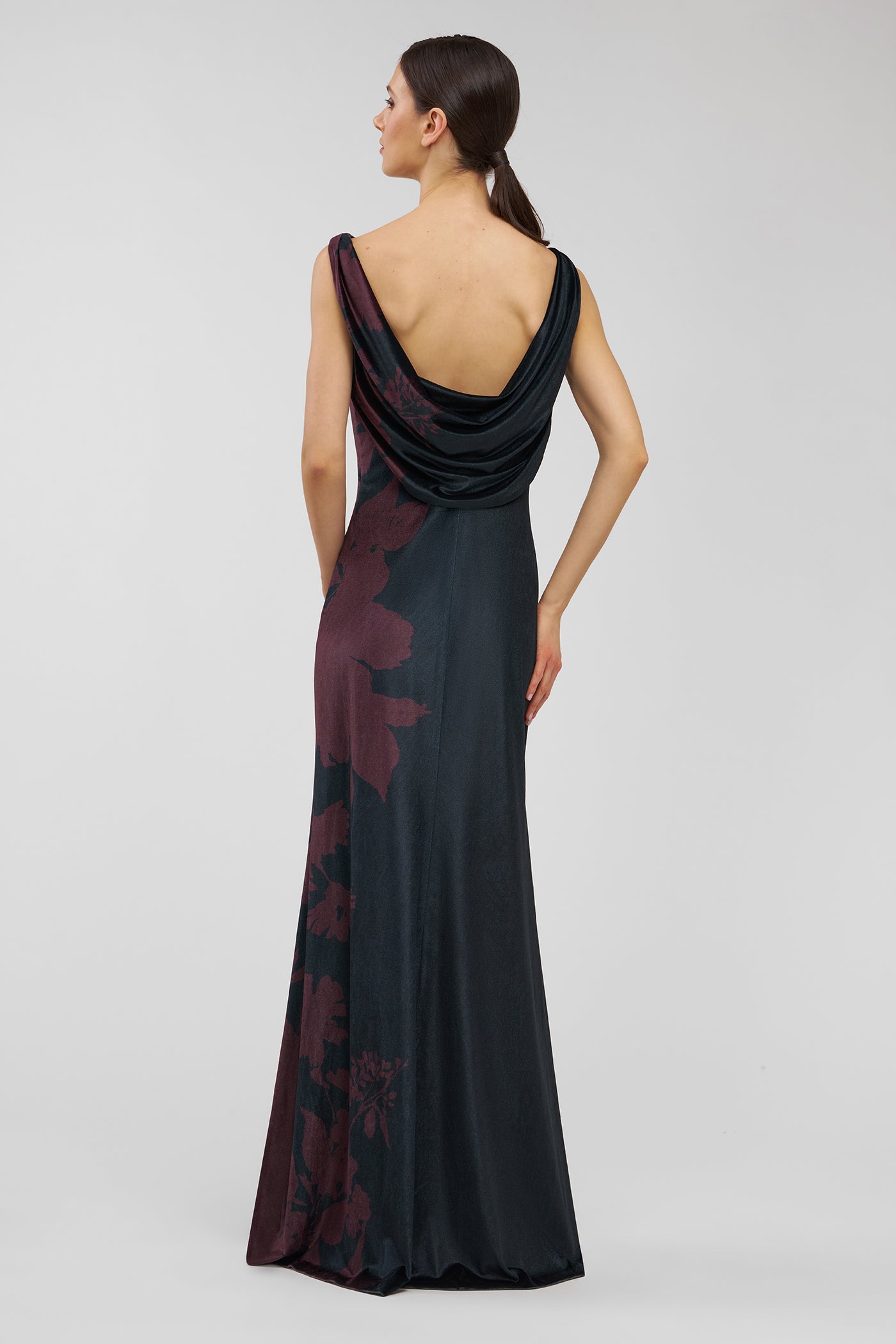 Woman wearing a black evening gown with floral patterns on a white background