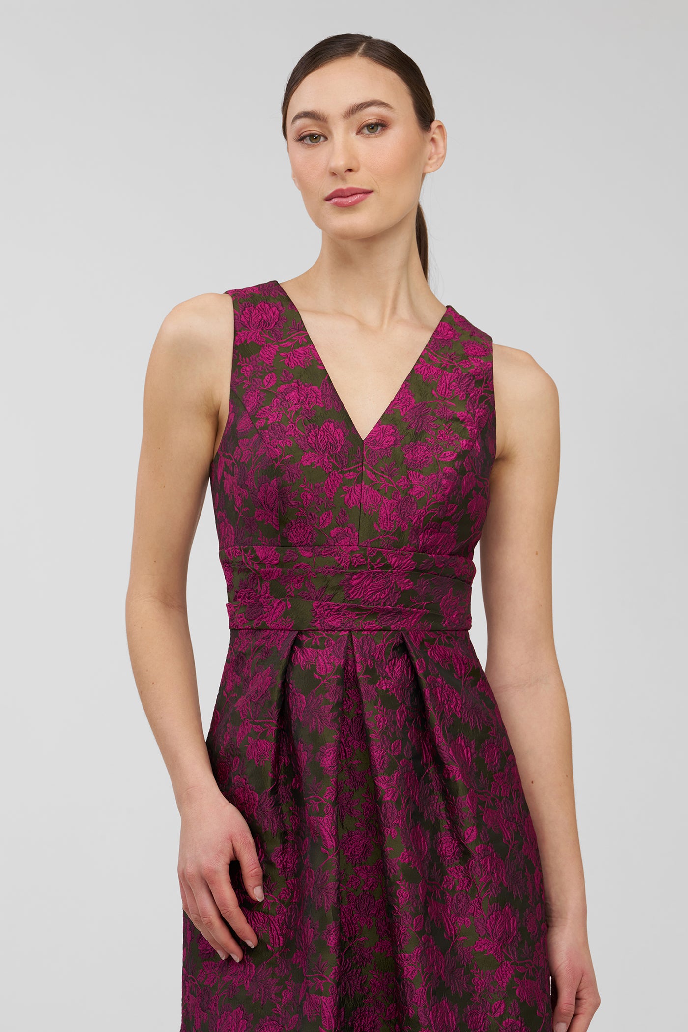 Woman wearing a sleeveless, floral-patterned dress on a plain background