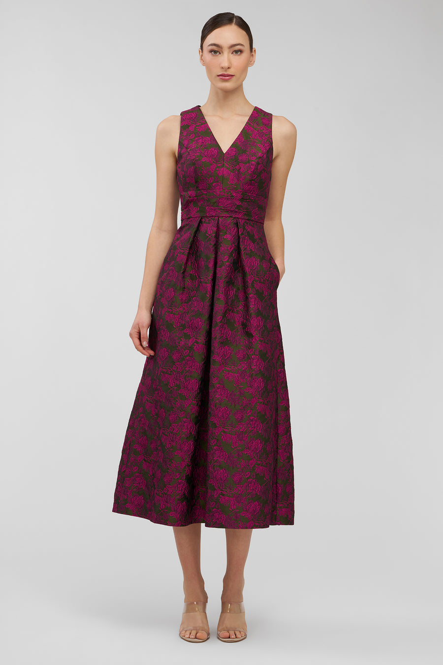 Woman wearing a sleeveless, patterned dress on a plain background