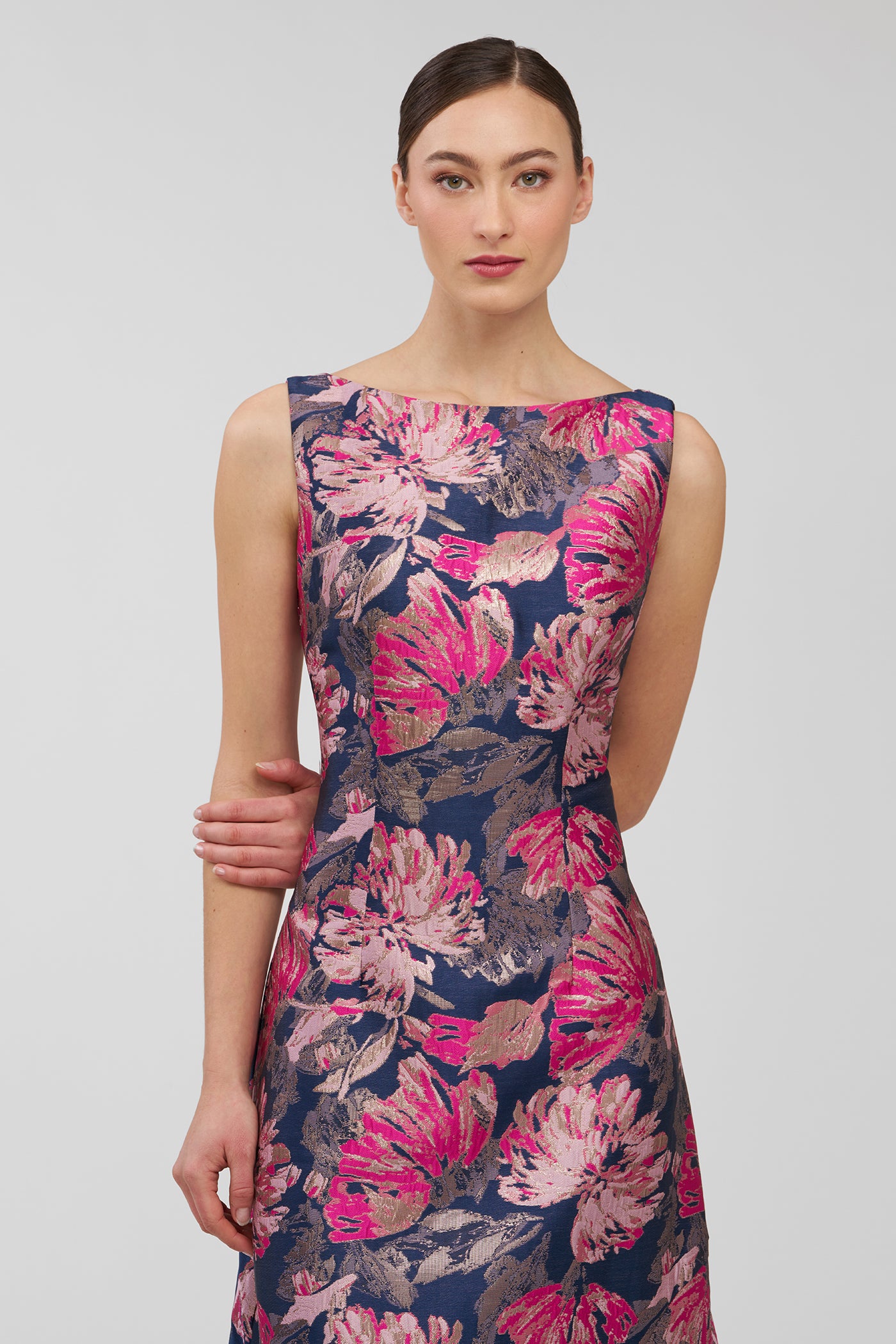 Woman wearing a sleeveless dress with pink floral pattern on a plain background