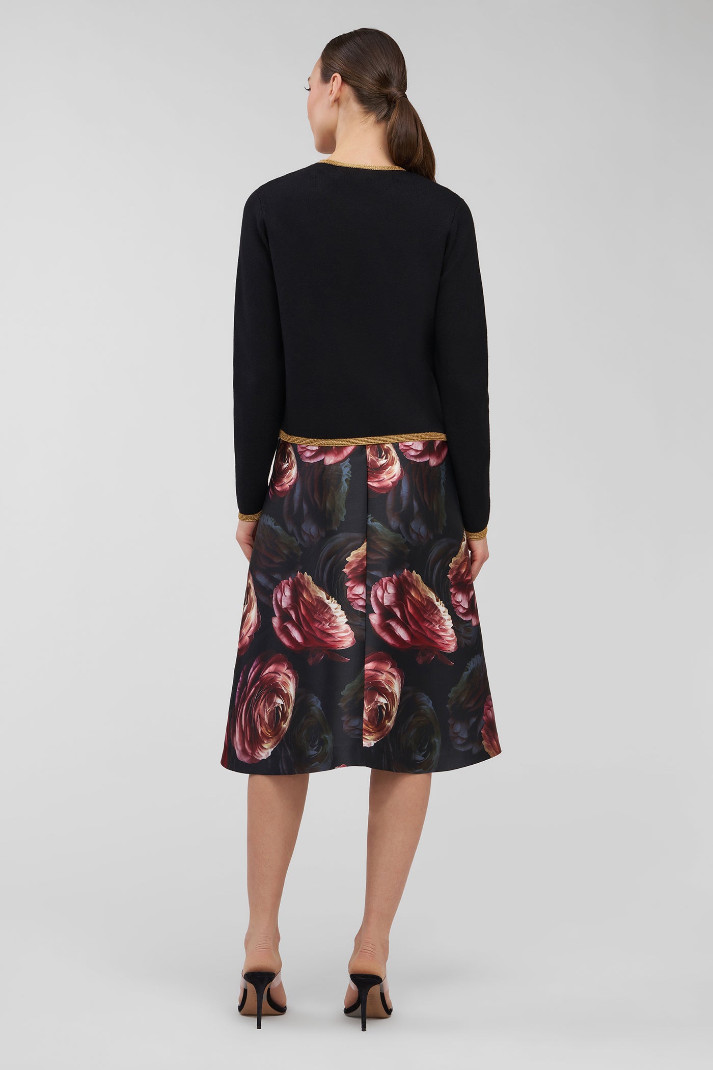 Woman wearing a cardigan top and floral dress on a white background