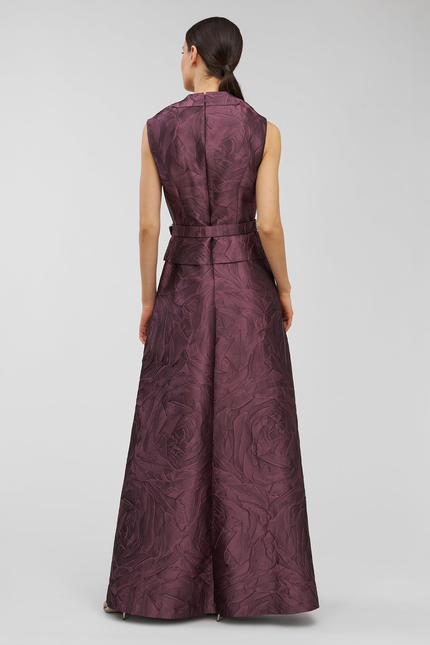 Woman wearing a long, patterned dress on a plain background