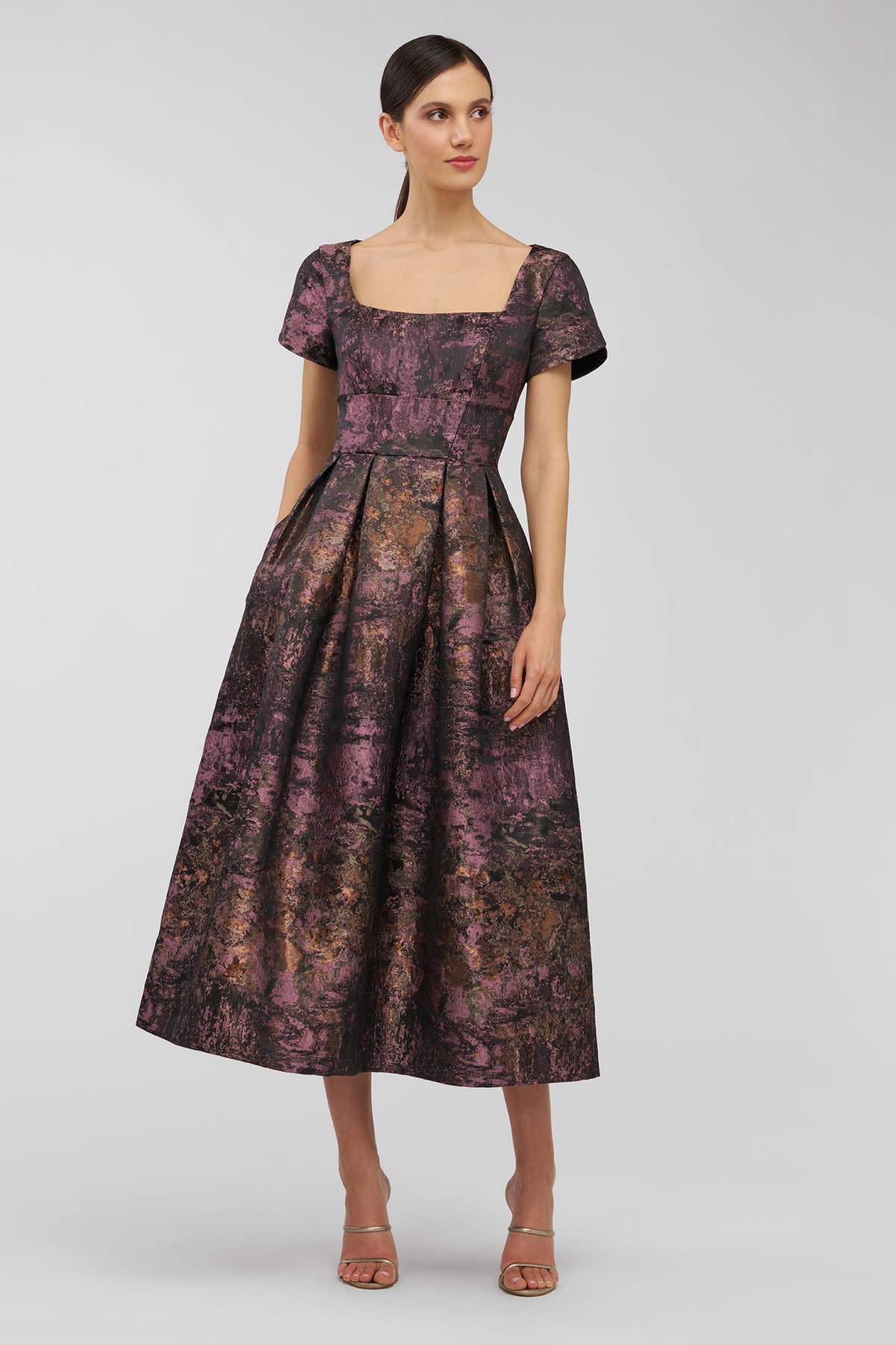 Woman wearing a patterned dress on a plain background