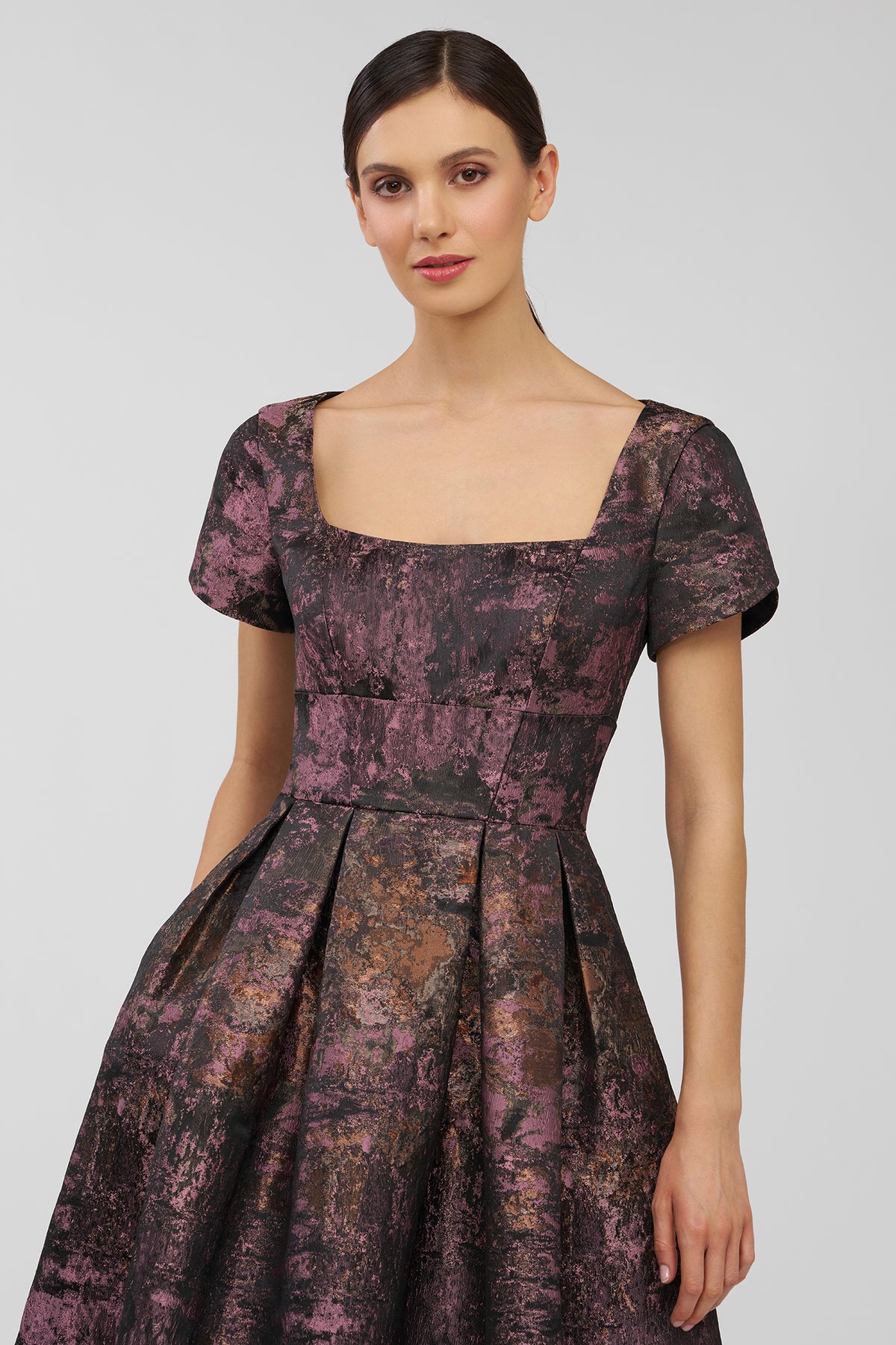 Woman wearing a patterned dress on a plain background