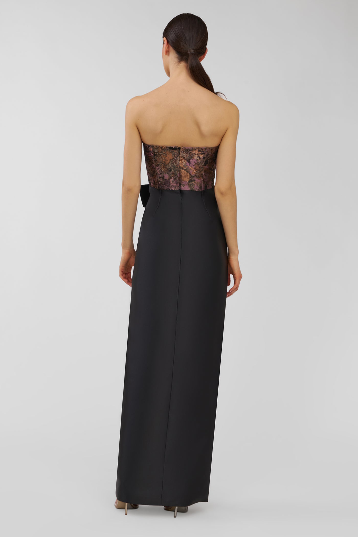 Woman wearing a black strapless evening gown with lace detailing on a white background