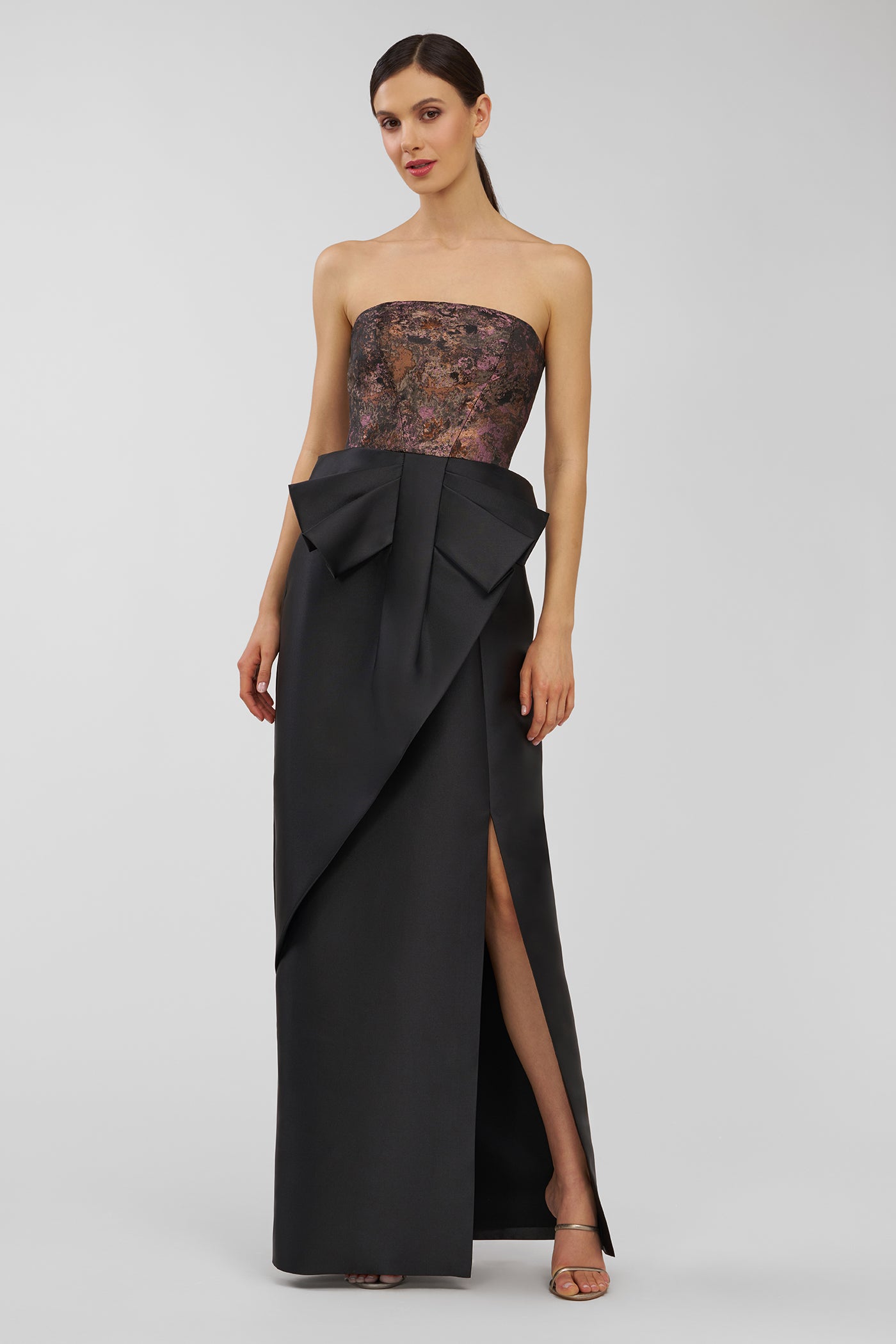 Woman wearing a strapless evening gown with a black overlay and lace bodice on a gray background