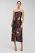 Woman wearing a strapless floral dress on a light gray background