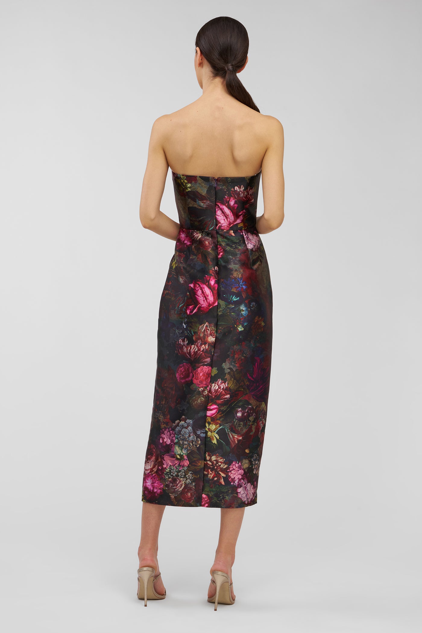 Woman wearing a strapless floral dress on a plain background