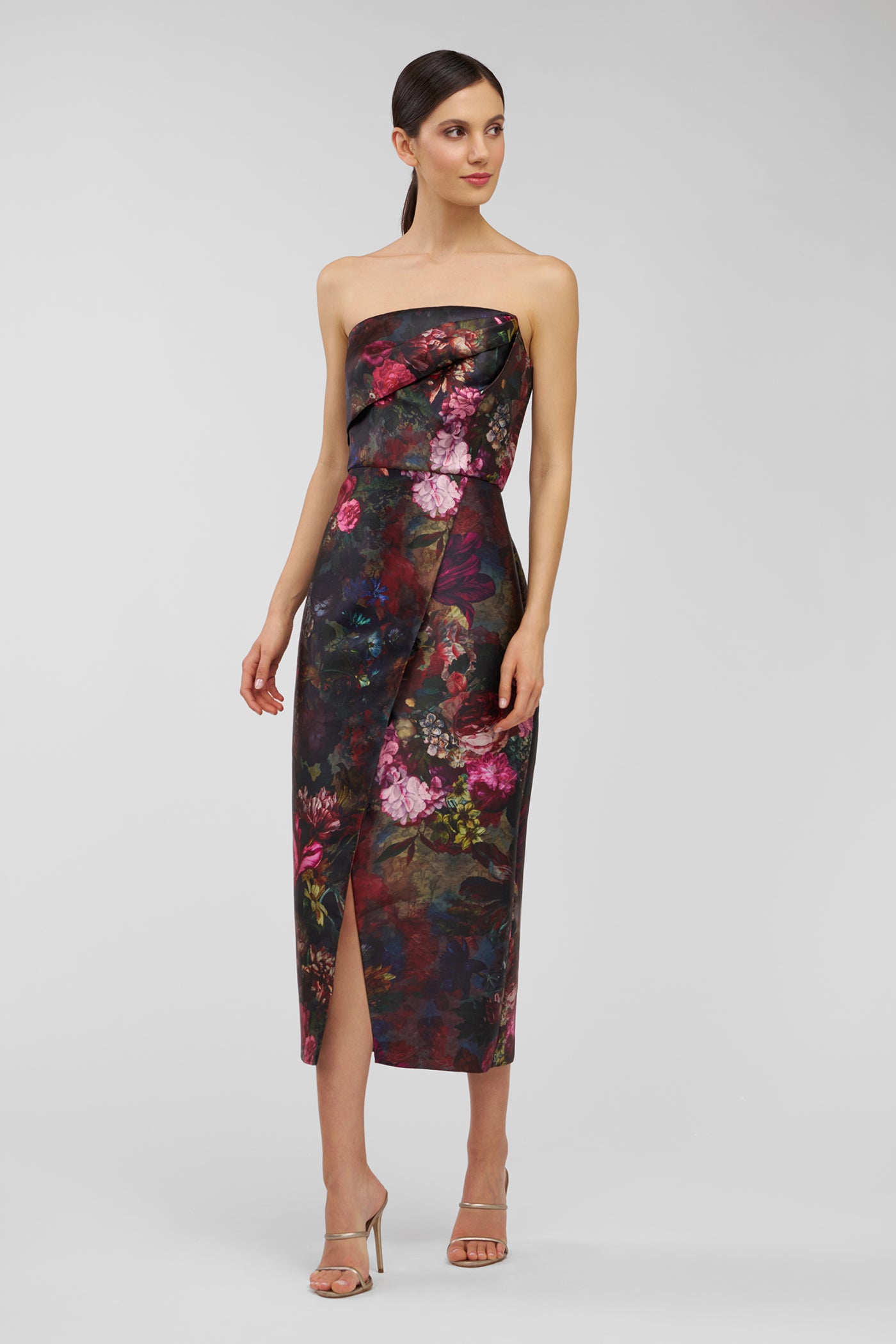 Woman wearing a strapless floral dress on a plain background