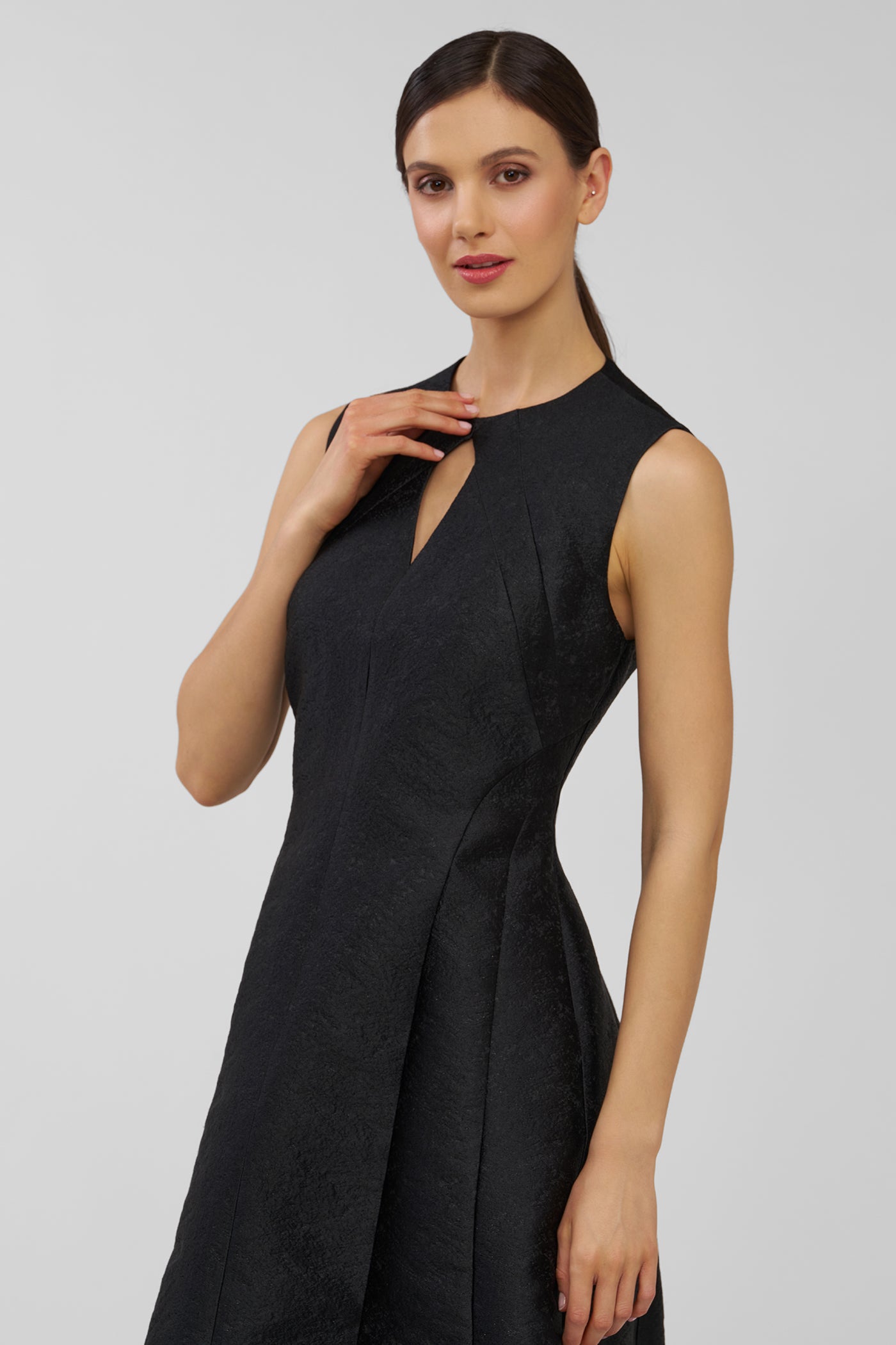 Woman wearing a black sleeveless dress against a plain background