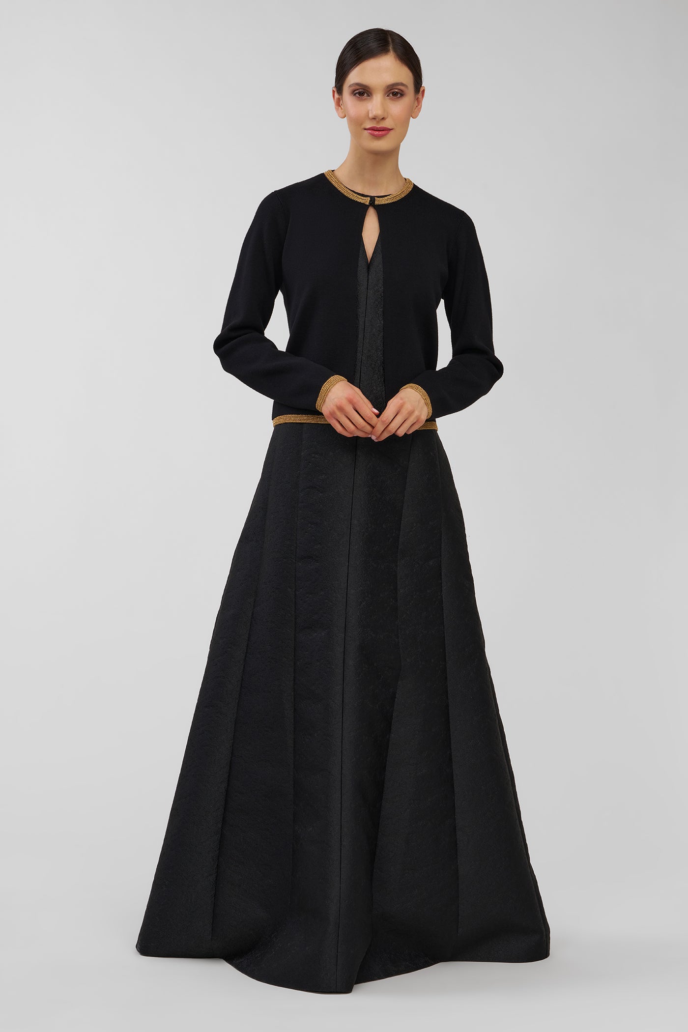 Woman wearing a black dress with a black cardigan on a gray background