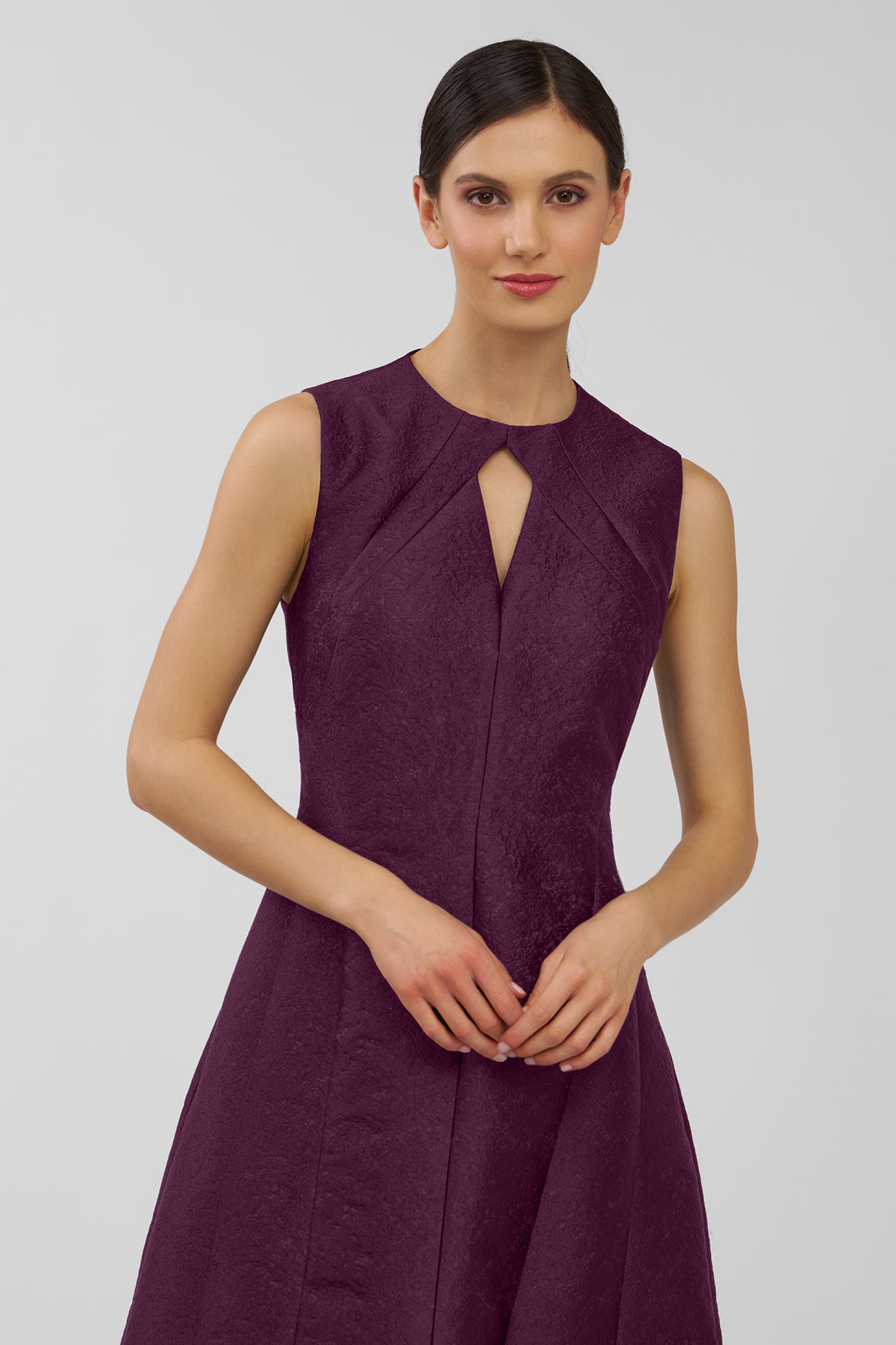 Woman wearing a purple sleeveless dress against a plain background