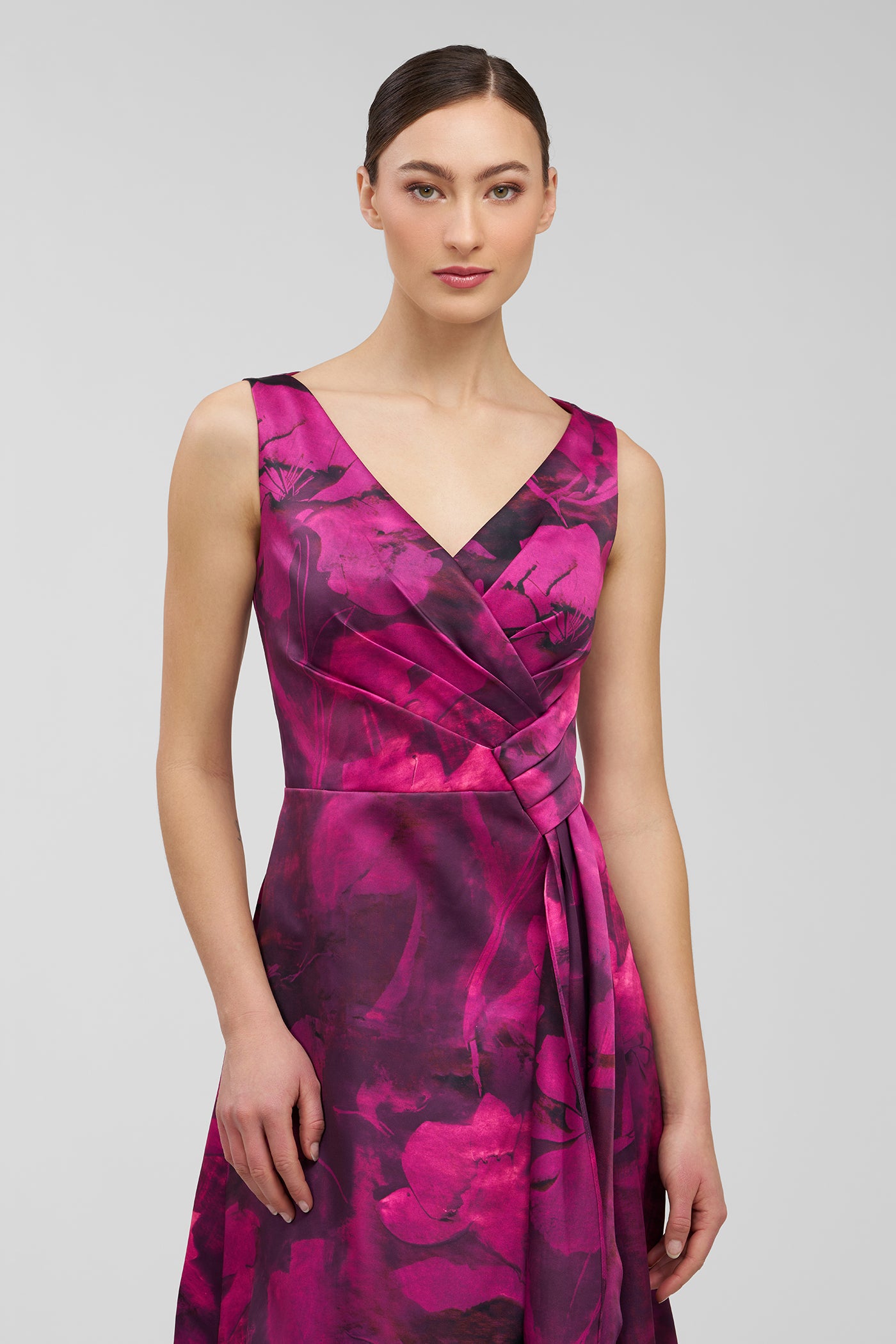 Woman wearing a vibrant pink and purple patterned dress on a light gray background