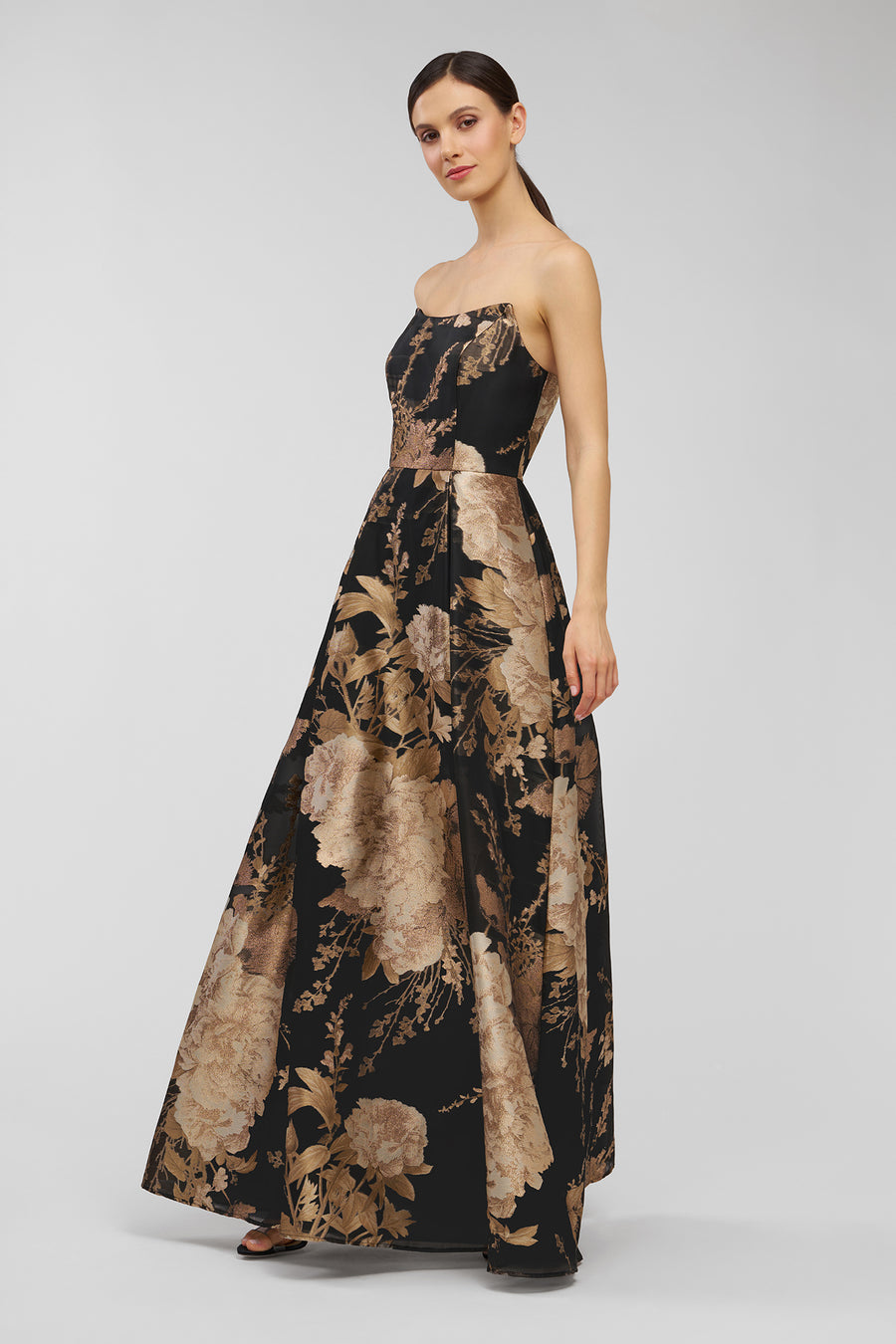Woman wearing a strapless floral gown on a white background