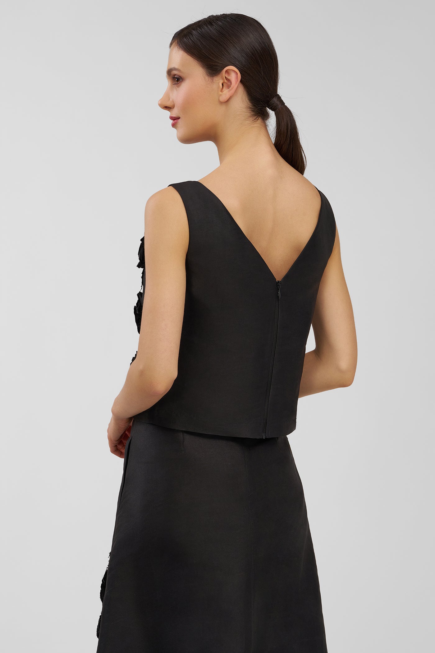 Woman wearing a black top with a V-neckline on a light gray background