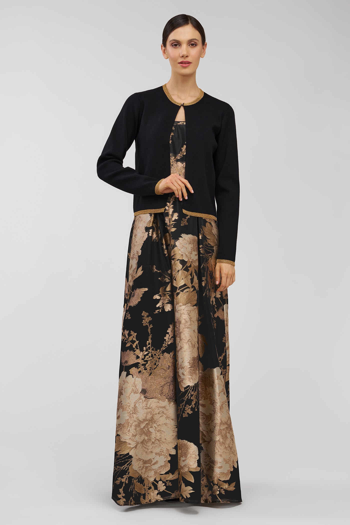 Woman wearing a black top and long, patterned gown on a gray background