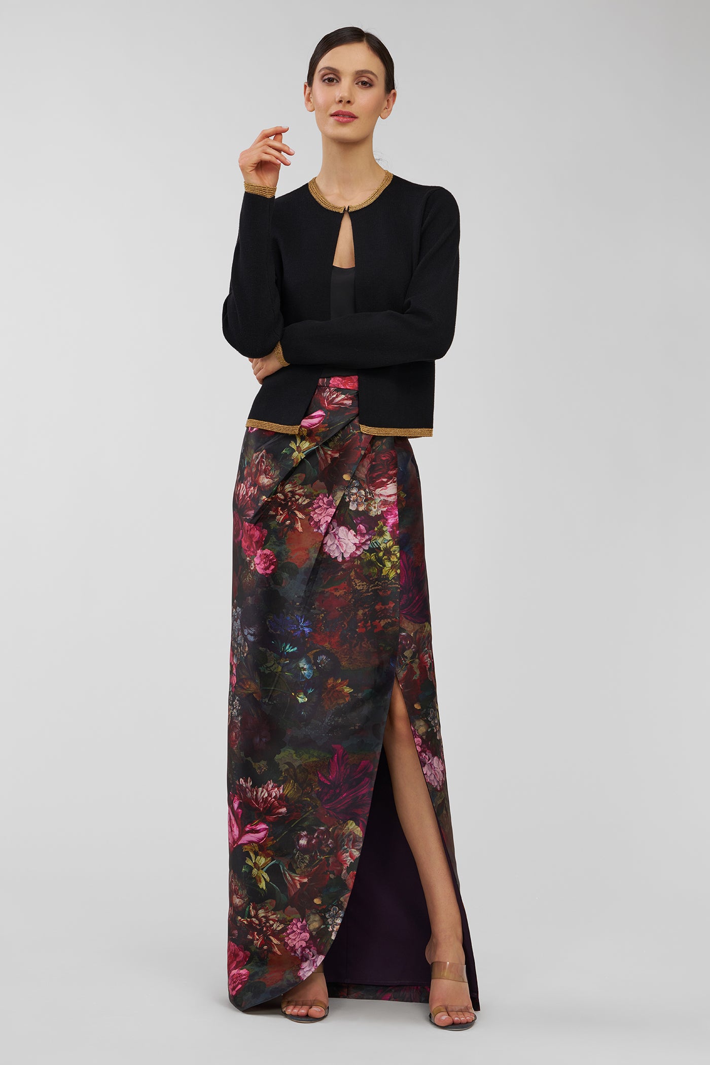 Woman wearing a black cardigan and floral gown on a white background