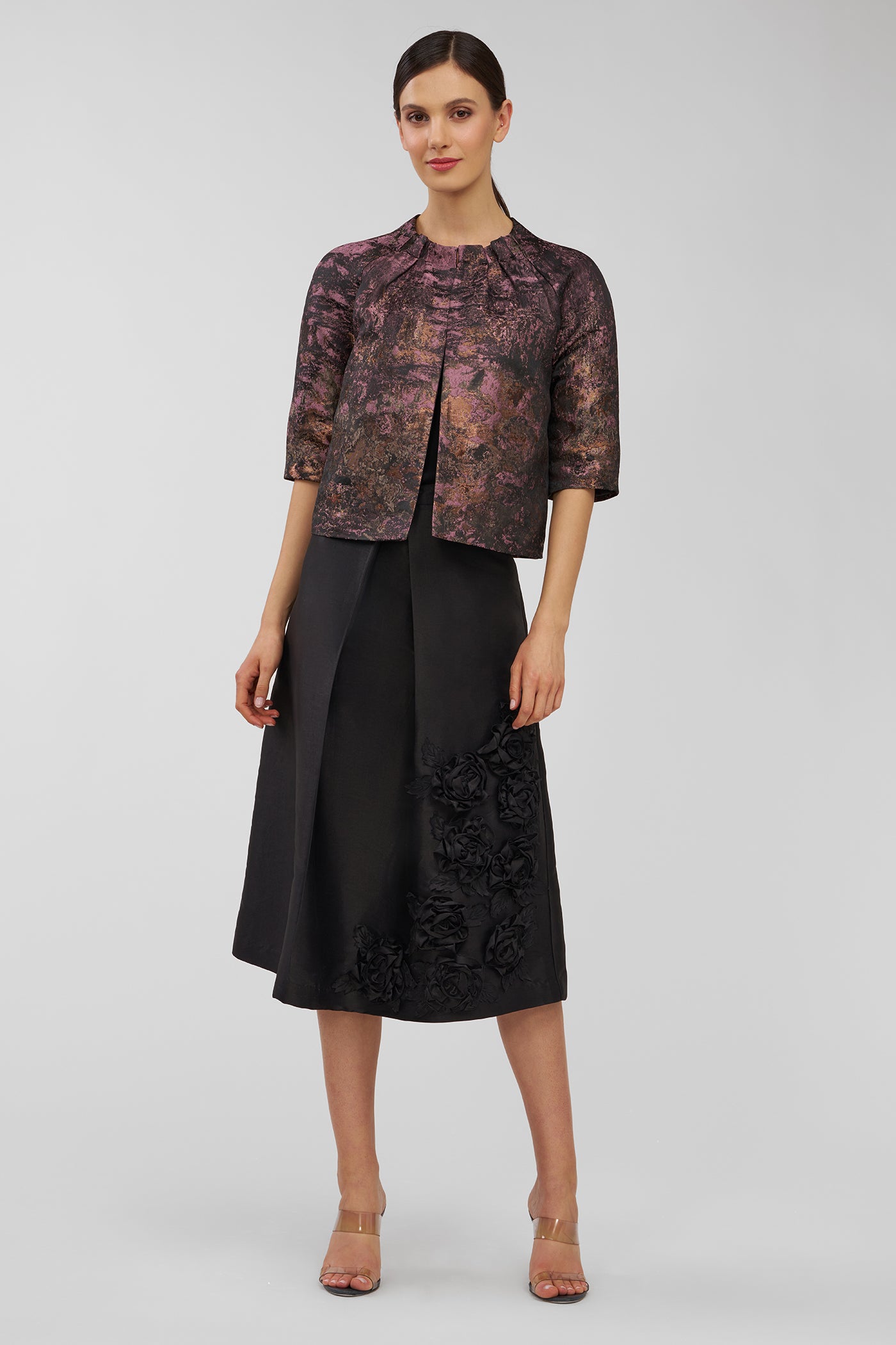 Woman wearing a patterned top and black skirt on a white background